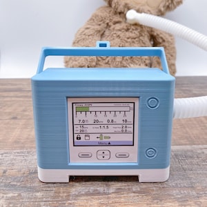 May include: A light blue medical device with a digital display showing various readings, including respiratory rate, tidal volume, and peak flow. The device has a white front panel with buttons and a handle. The display shows the date and time, 03/20/2023 08:43 AM.
