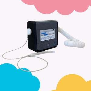 May include: A black medical device with a screen displaying various settings. It has a white hose and a thin, clear tube connected to it. The device is set against a backdrop of pink, blue, and yellow cloud shapes.
