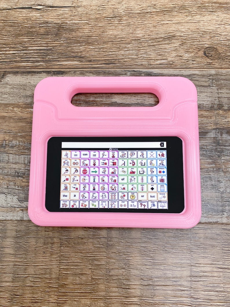 May include: A pink tablet case with a built-in handle surrounding a digital screen displaying a grid of communication icons and text labels. The interface features various symbols representing words, actions, and categories for speech assistance.