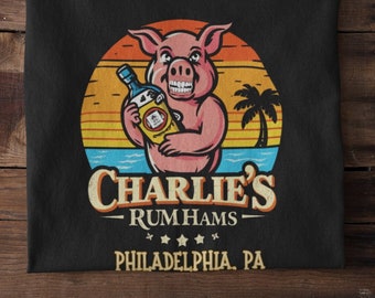 May include: Black t-shirt with a cartoon pig holding a bottle of rum in front of a sunset. The text "Charlie's Rum Hams Philadelphia, PA" is printed below the pig.