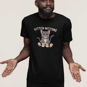 May include: A black t-shirt featuring the text "Kitten Mittons" and a cartoon image of a grey cat wearing mittens.