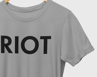 May include: A gray t-shirt with the word "RIOT" printed in black on the front.