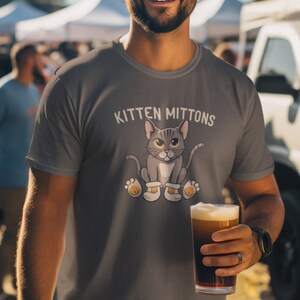 May include: A grey t-shirt featuring a cartoon cat wearing mittens and the text "Kitten Mittons".