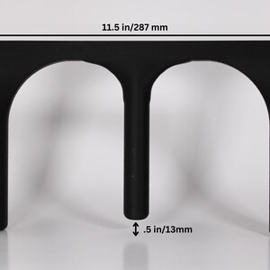 May include: Black plastic stand with two arched openings, measuring 287 mm wide, 170 mm tall, and 13 mm thick.