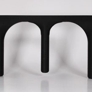 May include: Black plastic stand with two arches, designed to hold two items.