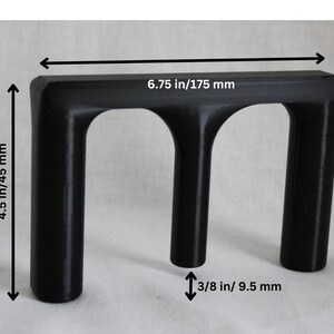 May include: Black plastic 3D printed object with three arches. The object measures 6.75 inches wide by 4.5 inches tall and 3/8 inch thick.