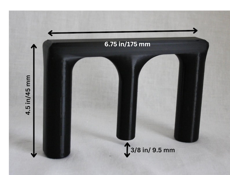May include: Black plastic 3D printed object with three arches. The object measures 6.75 inches wide by 4.5 inches tall and 3/8 inch thick.