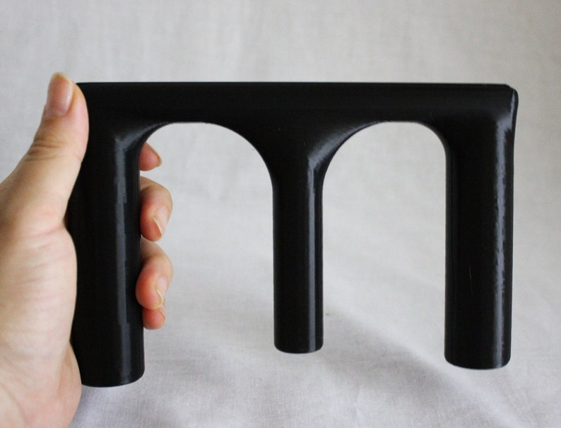 May include: Black plastic hand grip with three cylindrical openings.
