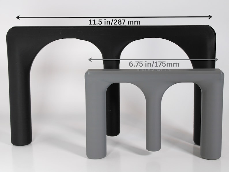 May include: Two black and grey plastic stands with arched openings. The larger stand measures 11.5 inches wide and the smaller stand measures 6.75 inches wide.