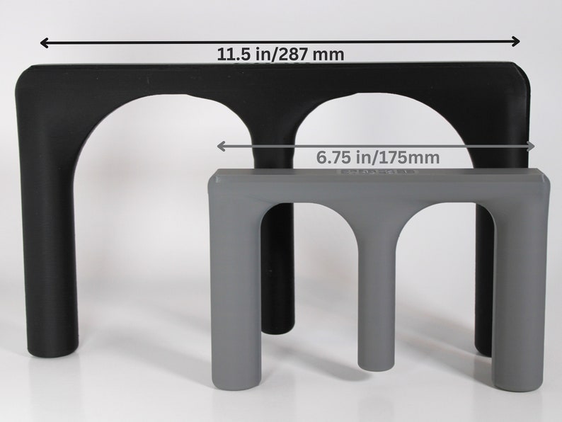 May include: Two black and gray plastic stands with arched openings. The larger stand measures 11.5 inches wide and the smaller stand measures 6.75 inches wide.