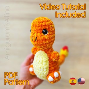 May include: An orange crocheted Charmander plushie with black eyes, white accents, and a yellow belly. The tail has red and yellow flames. Text on the image reads "Video Tutorial Included" and "PDF Pattern".