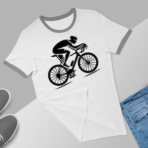 May include: White t-shirt with a black silhouette of a cyclist riding a bicycle. The t-shirt has a grey ringer.