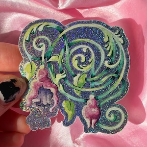 May include: A holographic sticker featuring a watercolor illustration of fuchsia flowers with pink and purple petals, intertwined with swirling green vines. The entire surface of the sticker has a sparkling, glittery finish that reflects light.