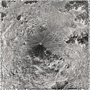 May include: A black and white photograph of a volcanic crater with a central peak. The crater is surrounded by a ring of smaller craters.