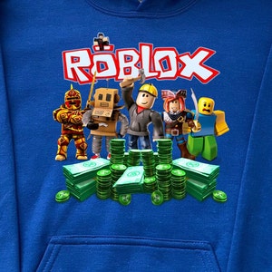May include: Blue hooded sweatshirt with a graphic print of the word "ROBLOX" in white and red letters. The graphic also features five cartoon characters from the game Roblox standing in front of stacks of green money.