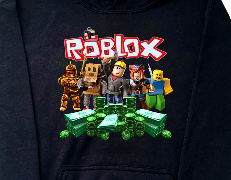 May include: Black hoodie with a graphic print of the word "ROBLOX" in red and white letters. The graphic also features cartoon characters from the game, including a knight, a robot, a builder, a pirate, and a blue character. The characters are standing on a pile of green money.
