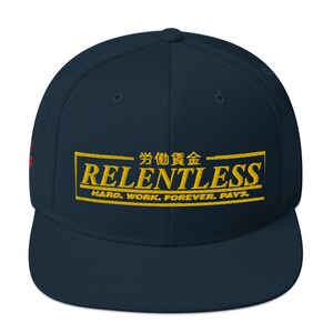 May include: A navy blue baseball cap with a gold embroidered logo that says "RELENTLESS" and "HARD. WORK. FOREVER. PAYS." in a yellow box. The logo also includes Japanese characters.