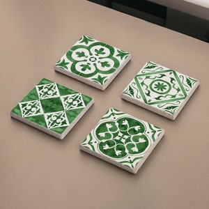 May include: Four square green and white ceramic coasters with intricate floral patterns.