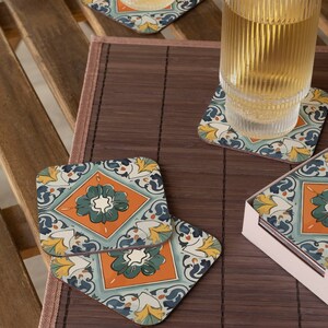 Puede incluir: Conjunto de cuatro posavasos cuadrados con un patr&oacute;n de azulejos coloridos. Los posavasos presentan un dise&ntilde;o azul, verde, naranja y amarillo. Los posavasos est&aacute;n sobre una estera de bamb&uacute; marr&oacute;n.