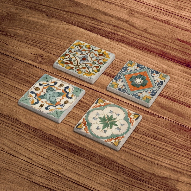 Puede incluir: Cuatro posavasos cuadrados de cer&aacute;mica con intrincados dise&ntilde;os florales en tonos azules, verdes, amarillos y naranjas. Los posavasos est&aacute;n colocados sobre una superficie de madera.