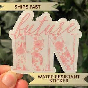 May include: A pink and white sticker with the words "future RN" in a script font. The letters "R" and "N" are filled with a floral pattern. The sticker is water resistant.