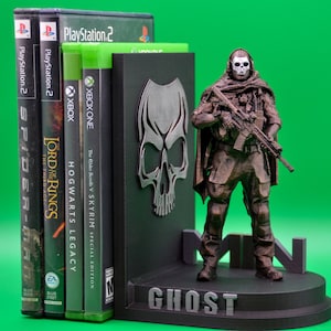 May include: A black and silver skull bookend with a 3D printed figurine of a soldier wearing a skull mask and holding a rifle. The bookend is labeled "GHOST".