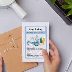 Op de afbeelding: Een blauwe en witte kaart met de titel "Urge Surfing" en een afbeelding van een surfer die op een golf surft. De kaart beschrijft een techniek om met drang om te gaan door de drang te identificeren, te observeren en de golf van de drang te berijden.