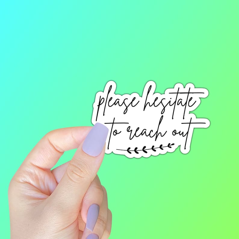 May include: White sticker with black text that reads "Please hesitate to reach out" with a small black floral design at the bottom. A hand is holding the sticker.