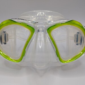 Op de afbeelding: Een helder duikmasker met een groene siliconen rok. Het masker heeft een heldere lens en een neuszak.