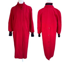 May include: A long red coat featuring a high collar, a single front button closure, and black ribbed knit cuffs. The back view displays a vertical row of four buttons extending down the center, complemented by a black ribbed knit collar detail.