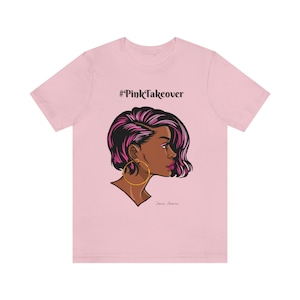 May include: Pink t-shirt with a graphic of a woman with pink and black hair, wearing large gold hoop earrings. The text '#PinkTakeover' is printed on the shirt.