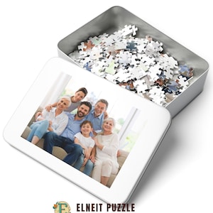 K&ouml;nnte beinhalten: Eine wei&szlig;e Metallbox mit offenem Deckel, die ein wei&szlig;es Puzzle enth&uuml;llt. Die Box hat ein Foto auf der Vorderseite von einer sechsk&ouml;pfigen Familie, die l&auml;chelnd auf einem Sofa sitzt.