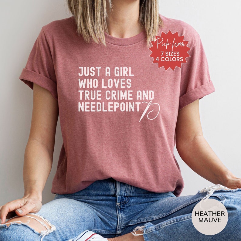 May include: A heather mauve t-shirt with the text "Just a girl who loves true crime and needlepoint" and a needle and thread graphic. The text "Pick from 7 sizes 4 colors" is on a red starburst.