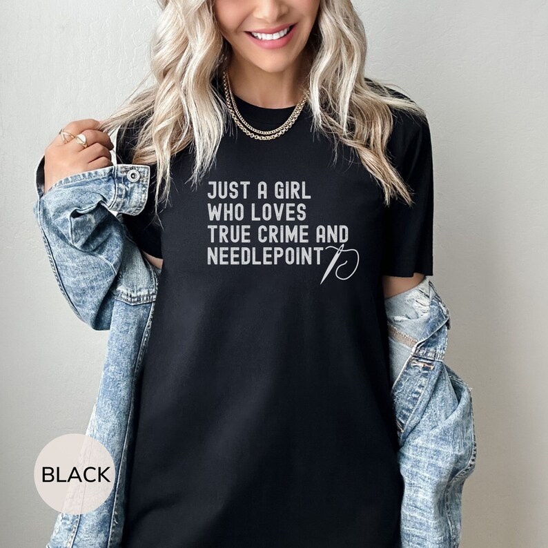 May include: Black t-shirt with the text "Just a girl who loves true crime and needlepoint" and a needle and thread design.