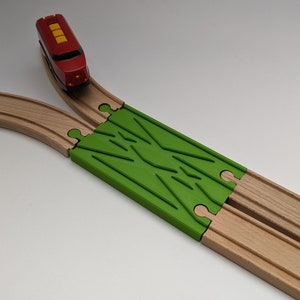 May include: A red toy train engine with yellow details is on a wooden train track with a green track switch. The train is about to go through the switch.