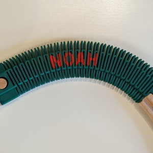 May include: A green flexible track section for a toy train set. The track is curved and has the word "NOAH" printed in red on the top.