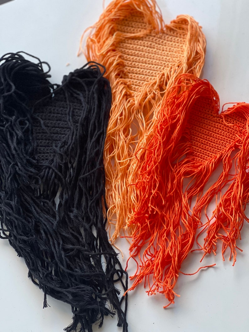 Puede incluir: Tres parches de coraz&oacute;n de ganchillo con flecos. Los parches son negros, naranja y melocot&oacute;n.