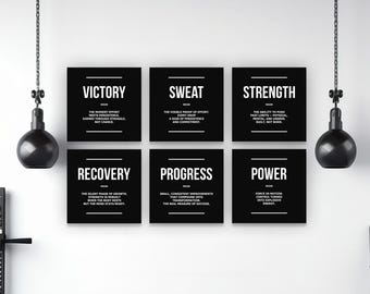 May include: Six black square motivational posters with white text, including "Victory," "Sweat," "Strength," "Recovery," "Progress," and "Power." Below, a row of black kettlebells sits on a shelf. The setting is a gym.