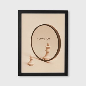 Peut inclure: Impression d'art encadrée avec un design conceptuel. Un pion et un roi blancs sont devant un miroir circulaire. Le miroir reflète le roi, et le texte "YOU VS YOU." est au-dessus du reflet. Le cadre est noir.