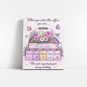 Puede incluir: Una impresión decorativa en lienzo con un arreglo floral en una cesta de madera, con mariposas y pájaros. El texto dice: "Cuando entras en esta oficina eres... Siempre eres... Bienvenido, Respetado, Valorado, Necesario, Apreciado."