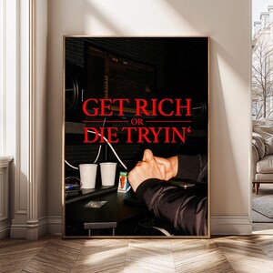 May include: A framed print with the text "GET RICH OR DIE TRYIN'" in red. The image shows a dark room with studio equipment, two white cups, and a person's hands. The overall theme is music and recording.