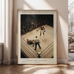 Pode incluir: Um cartaz emoldurado com uma fotografia de ângulo alto de uma luta de boxe com um pugilista em pé sobre um oponente no ringue. O texto diz THE COUNT no topo e The moment confidence become immortal. - Boxing History na parte inferior.
