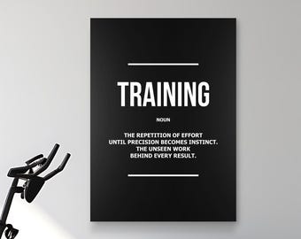 Puede incluir: Un póster negro con la palabra "TRAINING" en letras blancas. El póster incluye una definición de entrenamiento. En la imagen se ven una bicicleta estática y pesas. El fondo es blanco.