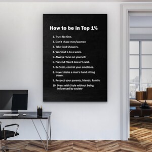 May include: A black framed canvas print with white text that reads "How to be in Top 1%" followed by a list of ten rules. The print is hanging on a white wall in a room with a desk and a computer.