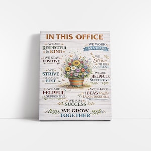 Op de afbeelding: Een houten bord met de tekst "IN THIS OFFICE" bovenaan. Het bord toont een bloemstuk in een pot en verschillende zinnen zoals "We are Respectful & Kind" en "We Grow Together."
