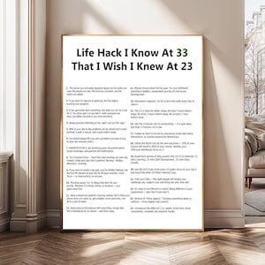 Puede incluir: Un póster enmarcado con el texto "Life Hack I Know At 33 That I Wish I Knew At 23". El póster contiene 24 consejos numerados para la superación personal, escritos en negro sobre fondo blanco. El marco es marrón.