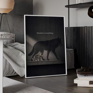 May include: A framed vertical wall art print featuring a small wolf pup walking on a ledge with a large, dark shadow of a full-grown wolf cast on the wall behind it. The text "Mindset is everything." is printed in white above the wolf shadow.