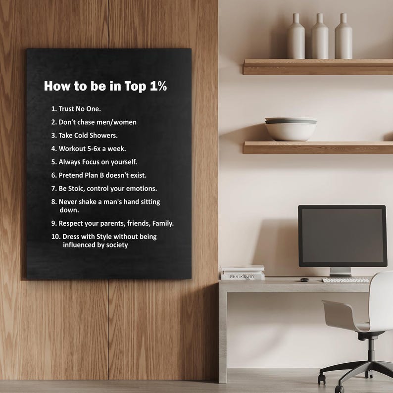 May include: A black framed sign with white text that reads "How to be in Top 1%" followed by ten bullet points. The sign is mounted on a wooden wall. A desk with a computer and chair is in the background.