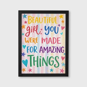 Op de afbeelding: Een ingelijste print met een zwarte rand toont de kleurrijke tekst "BEAUTIFUL girl, YOU WERE MADE FOR AMAZING THINGS". De achtergrond heeft verticale strepen in pastelkleuren, met sterren en harten.
