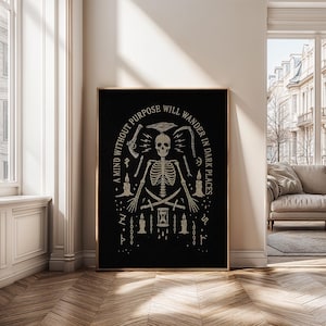 May include: Black framed art print featuring a skeletal figure with various occult symbols. The artwork includes the text "A mind without purpose will wander in dark places" in a stylized font. The design is in shades of beige and black.